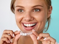 Smiling woman placing Invisalign tray