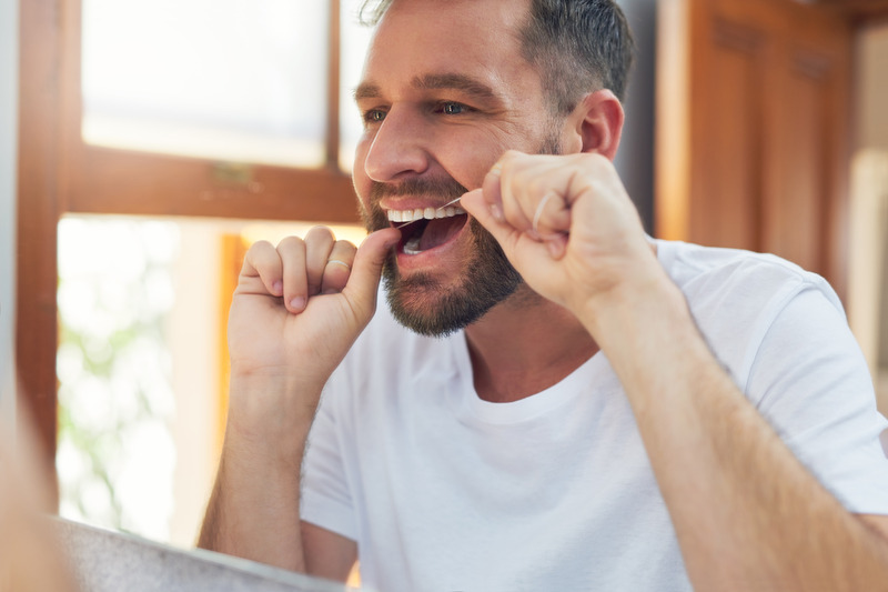 Patient flossing after removing Invisalign aligners